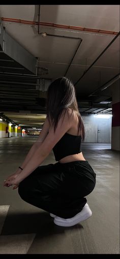 a woman kneeling down in an empty parking garage