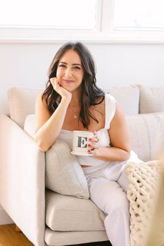 a woman sitting on a couch holding a coffee mug