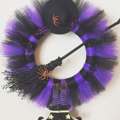 a purple and black halloween wreath with a top hat, broom, and spider on it