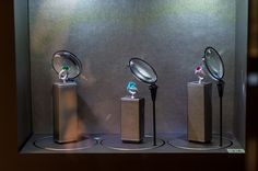 three different types of magnifying glasses on display in a glass case with metal bases