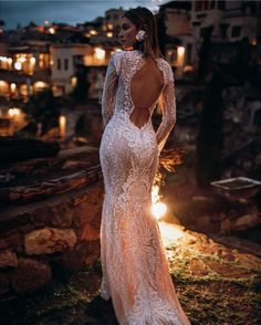 a woman in a white wedding dress standing on top of a hill with her back to the camera