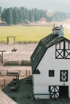 a white barn with horses in the background