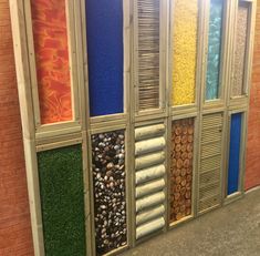 a wall that has different colored windows on it and rocks in the bottom right hand corner