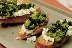 two pieces of bread with broccoli and cream cheese on them sitting on a tray