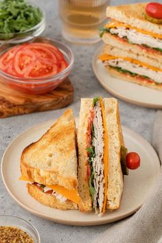 a sandwich cut in half sitting on top of a white plate next to other plates