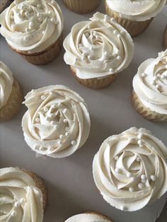 cupcakes with white frosting sitting on a baking sheet