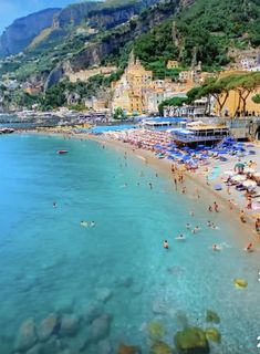 the beach is crowded with people and umbrellas near the water's edge, as seen from above