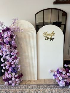 purple flowers are arranged in front of a white arch with the word bride to be written on it