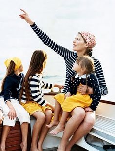 a group of women sitting on top of a boat next to each other in front of the ocean