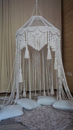 there is a white bed with pillows on the floor and a canopy made out of macrame