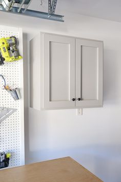 a workbench with tools hanging on the wall and pegboard in the background