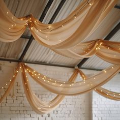 the ceiling is decorated with lights and draping for an elegant wedding or special event