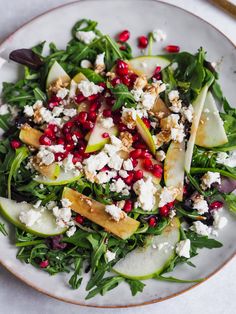 a salad with apples, pears and feta cheese on a white platter