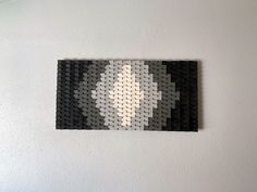 a piece of art made out of legos is hanging on the wall next to a lamp