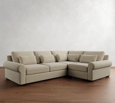 a large sectional couch with pillows on the back and sides, in front of a white wall