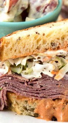 a close up of a sandwich on a plate with coleslaw in the background