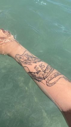 a person's arm in the water with tattoos on it