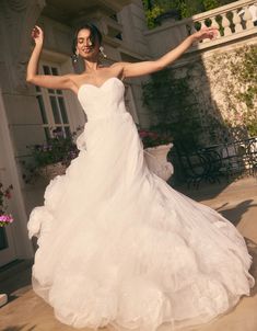 a woman in a white wedding dress posing for the camera with her arms spread out