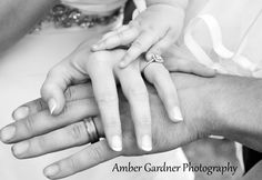 a black and white photo of a family holding their child's hands together with the mother holding her baby