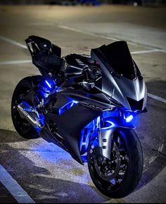 a motorcycle parked in a parking lot with blue lights on it's front wheel