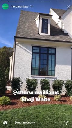 a white house with black windows and bushes in the front yard is featured on an instagram page