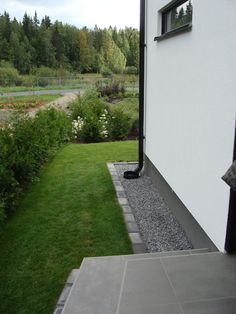 an open door leading to a white house with green grass and trees in the background