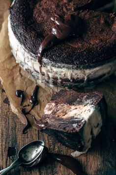 a chocolate cake sitting on top of a wooden table next to a spoon and fork