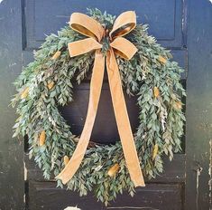 a wreath is hanging on the front door with a ribbon around it's edge