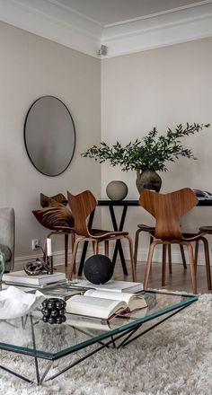 a living room filled with furniture and a glass coffee table in front of a mirror