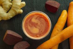 carrots, beets and other vegetables on a table with sauce in a bowl