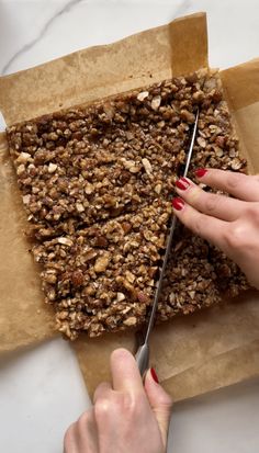 a woman cutting up some food with a pair of scissors on top of parchment paper