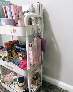 a white cart filled with lots of items on top of a carpeted floor next to a wall