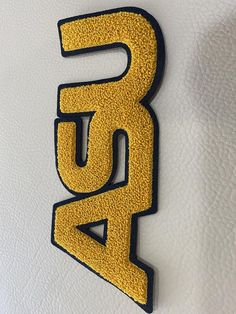 the letter b is made out of yellow and black glittery material with an arrow on it