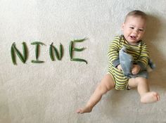 a baby is sitting on the floor and holding a stuffed animal in front of the word nine