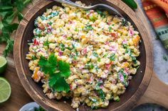 a wooden bowl filled with corn salad and garnished with cilantro