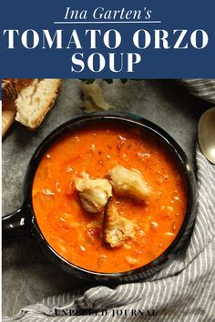 tomato orzo soup in a black bowl with bread on the side