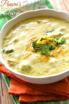 a bowl of soup with broccoli and cheese in it on a green napkin