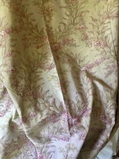 an unmade bed with pink and white floral print on it's coverlet