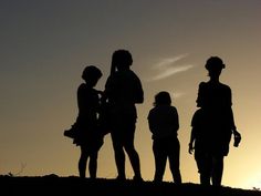 the silhouettes of four people standing on top of a hill