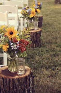 flowers in vases sitting on top of wooden stumps