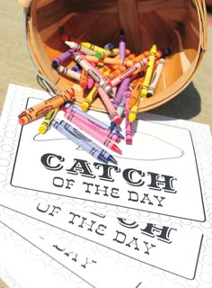 a bucket full of crayons sitting on top of a table next to a sign that says catch of the day