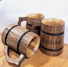 three wooden mugs sitting on top of a table next to each other with the word manhattan engraved on them