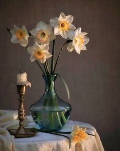 a vase filled with white flowers sitting on top of a table next to a candle