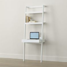 a white shelf with a computer on top of it in front of a plain wall