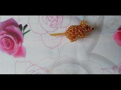 a gold mouse brooch sitting on top of a white tablecloth with pink roses