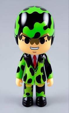 a green and black figurine wearing a suit with polka dots on it's head