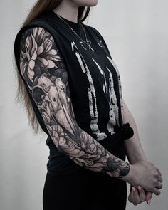 a woman with a tattoo on her arm and shoulder is standing in front of a white wall