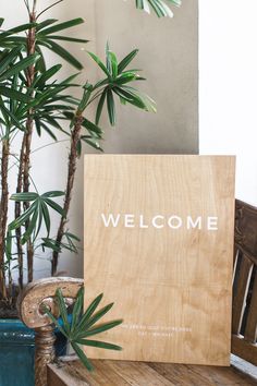 a welcome sign sitting on top of a wooden bench next to a potted plant