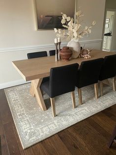 a dining room table with black chairs and a white rug