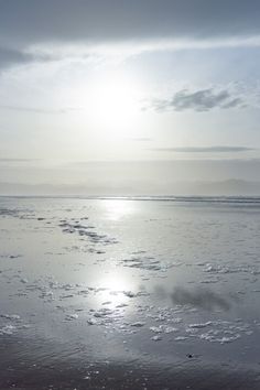 the sun shines brightly in the sky over an ocean beach with ice floes